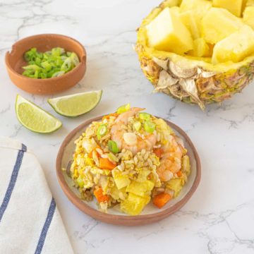 Pineapple fried rice served with a pineapple bowl in the background.