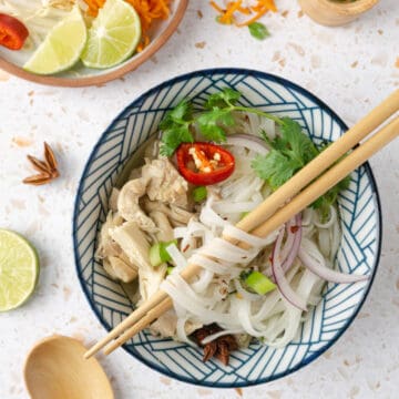 A bowl of chicken pho with chopsticks twirled around the noodles.