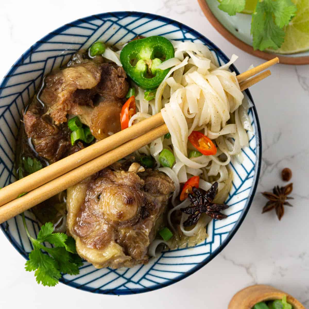 A bowl of pho noodles with chopsticks propped across wrapped around some noodles.