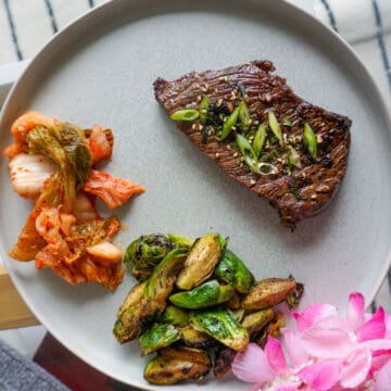 A plate with kalbi, kimchi, and brussels sprouts.