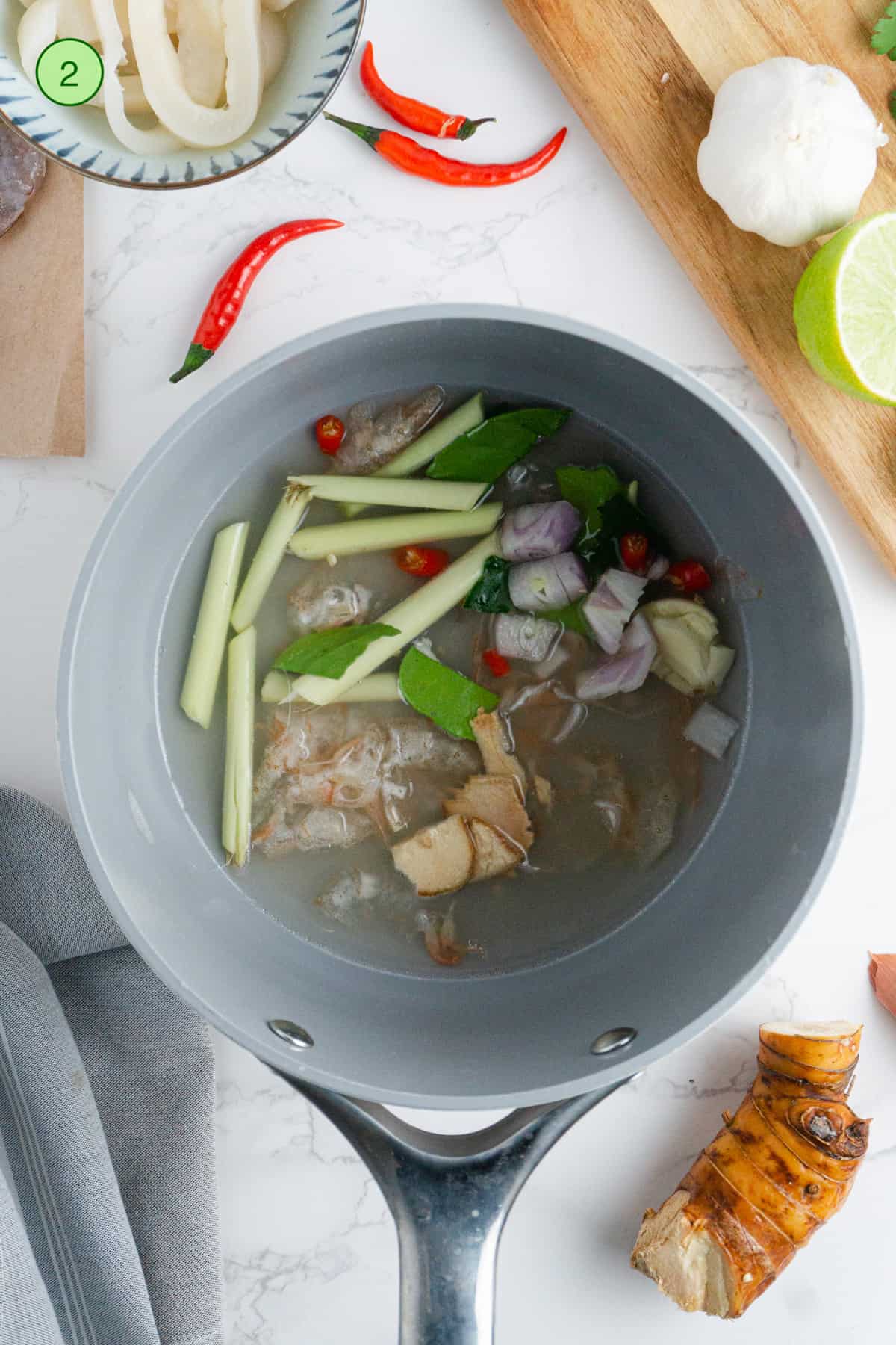 Adding the aromatics and herbs in the saucepan.