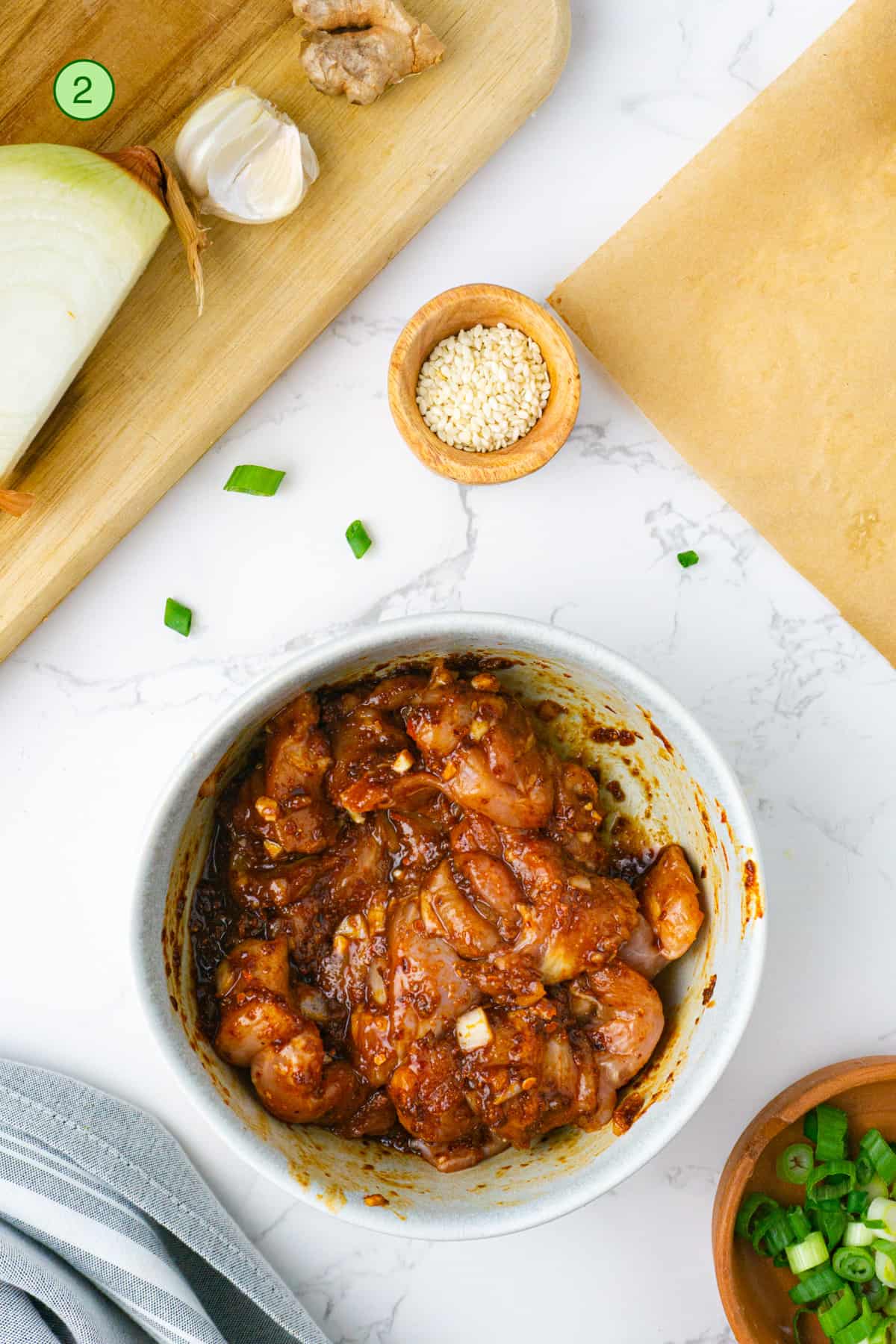 Raw chicken mixed with the spicy bulgogi marinade in a bowl.