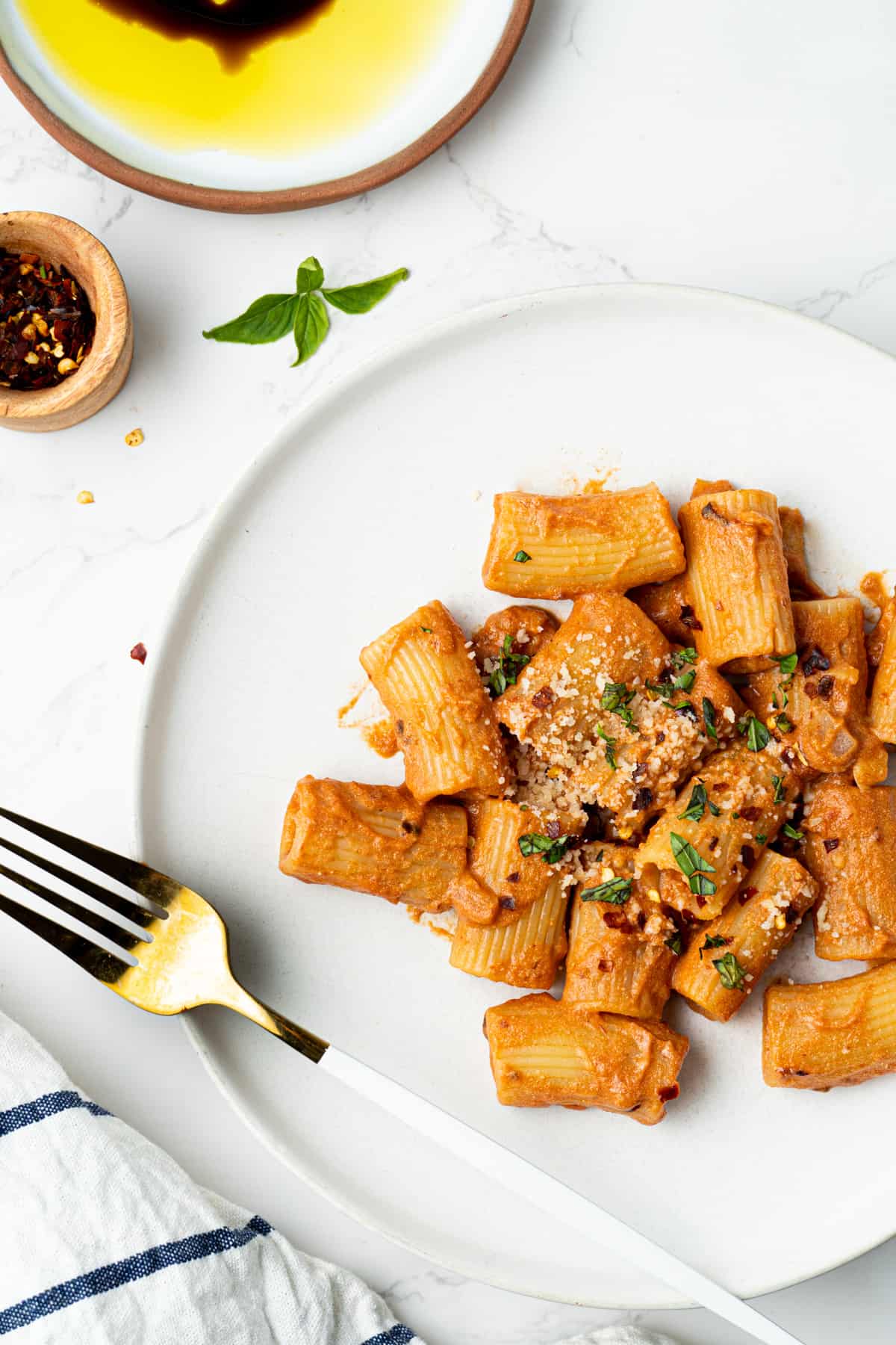 Spicy rigatoni with red pepper flakes and olive oil plate on the side.