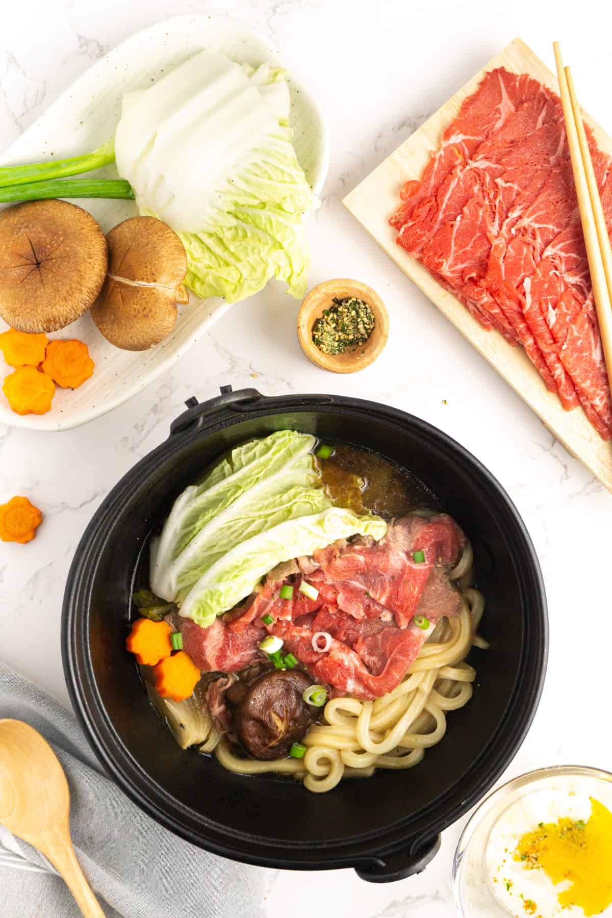 A cast iron bowl filled with sukiyaki beef and vegetables.