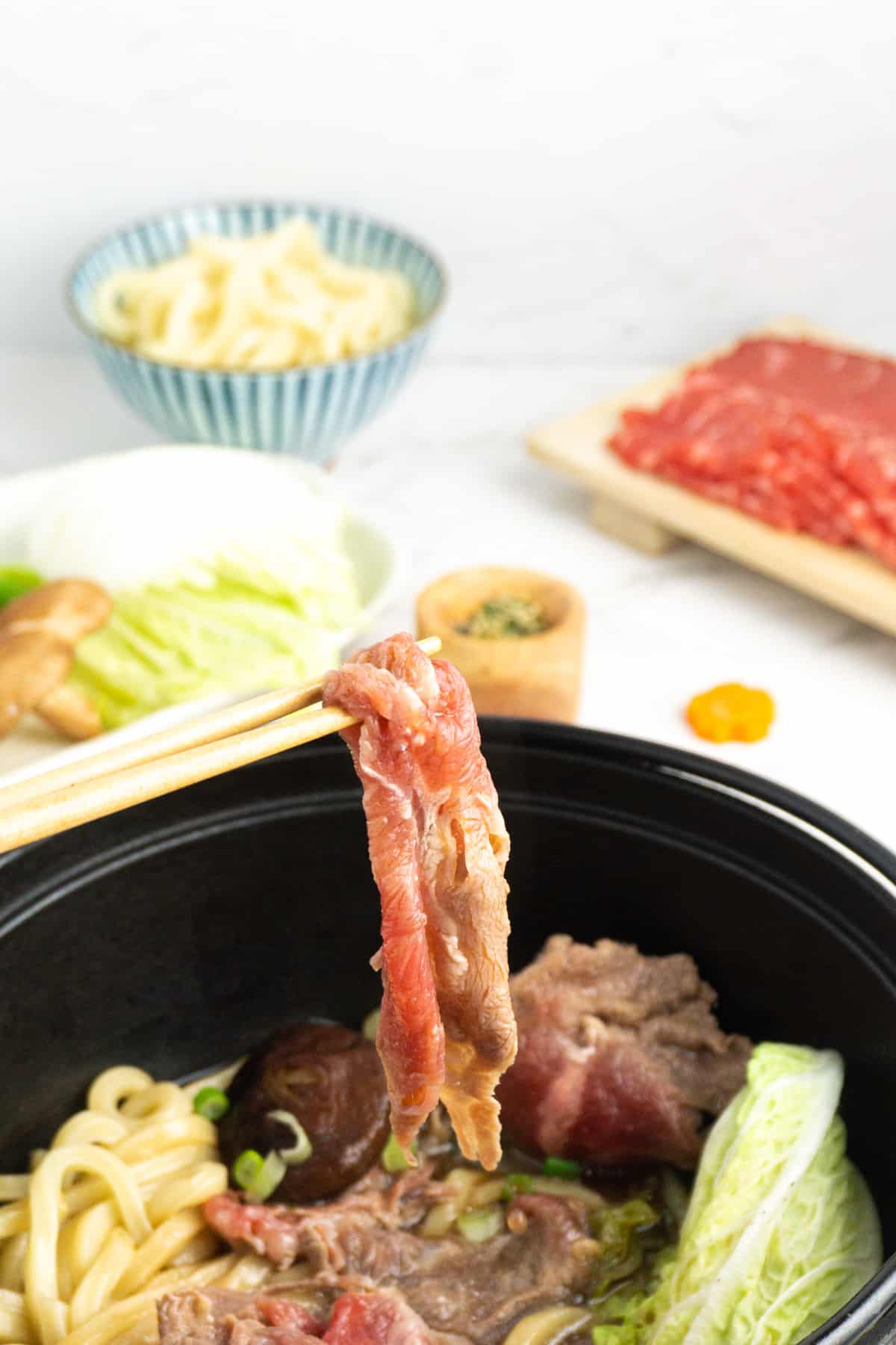 Dipping a slice of beef into the sukiyaki hot pot.