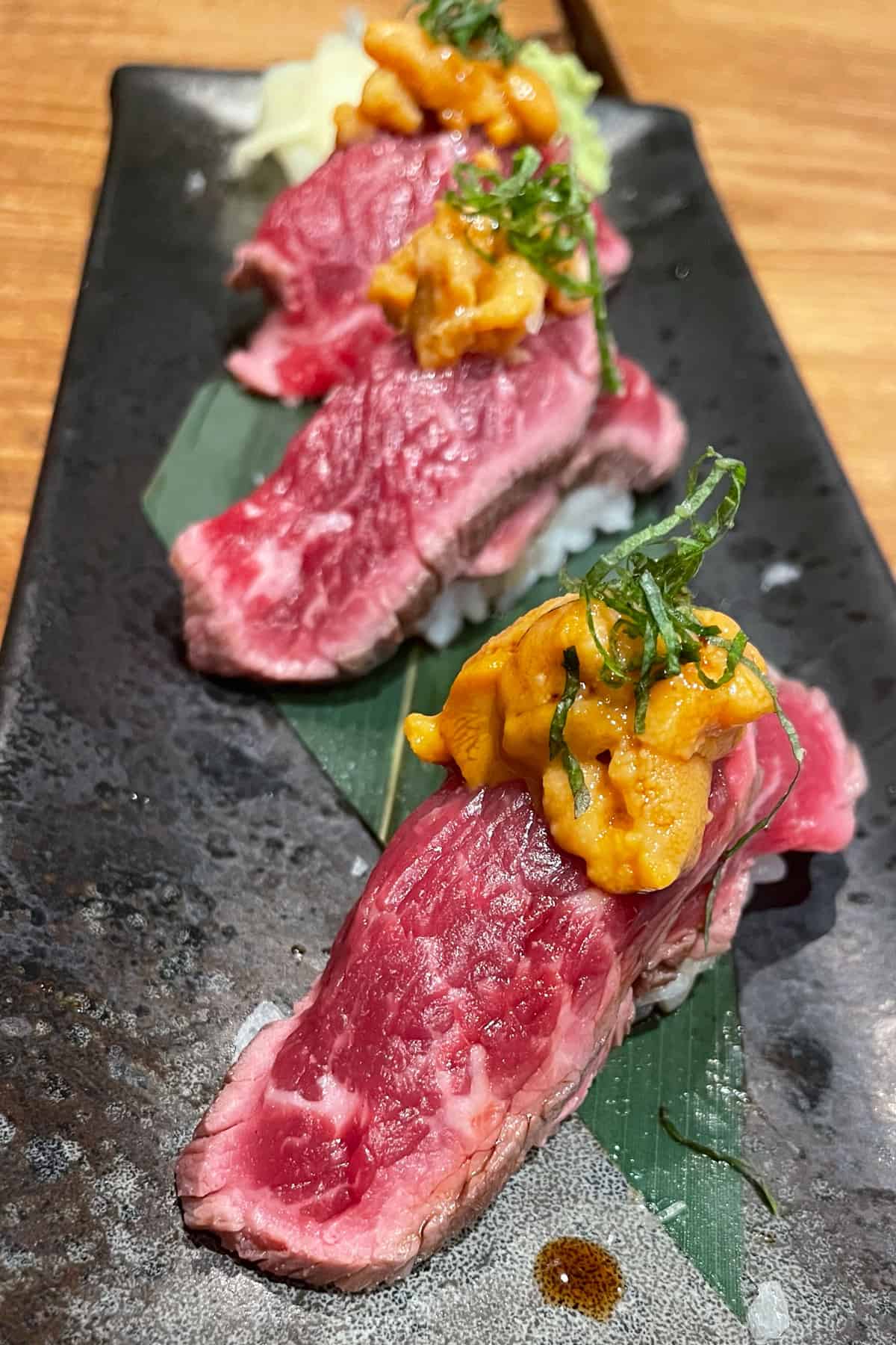 Beef and uni sushi on a long plate.