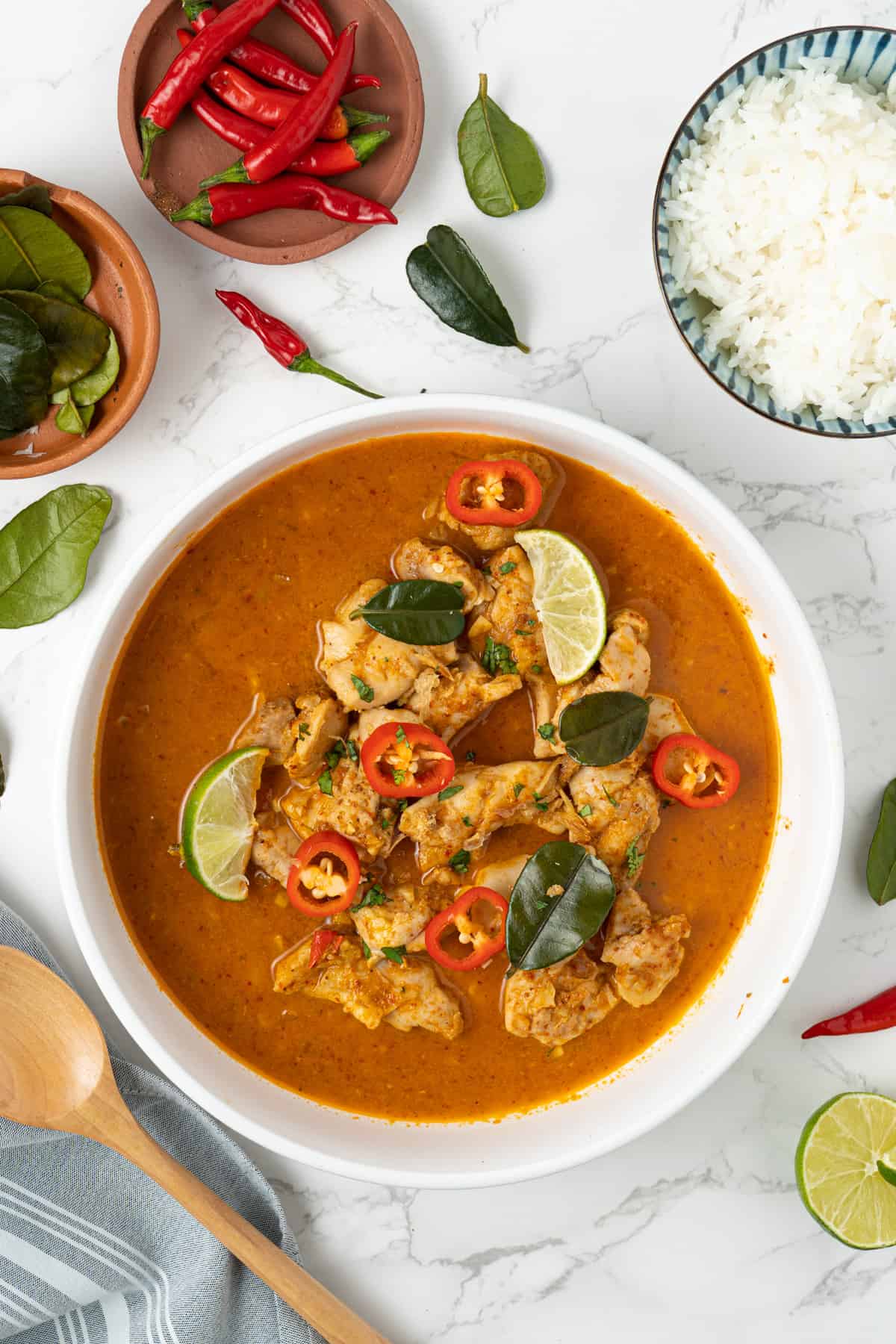 Overhead shot of the red thai chicken curry garnished with red peppers and lime leaves.