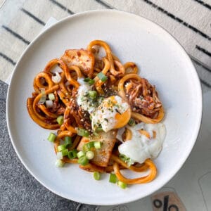 A plate of kimchi udon with a poached egg on top.
