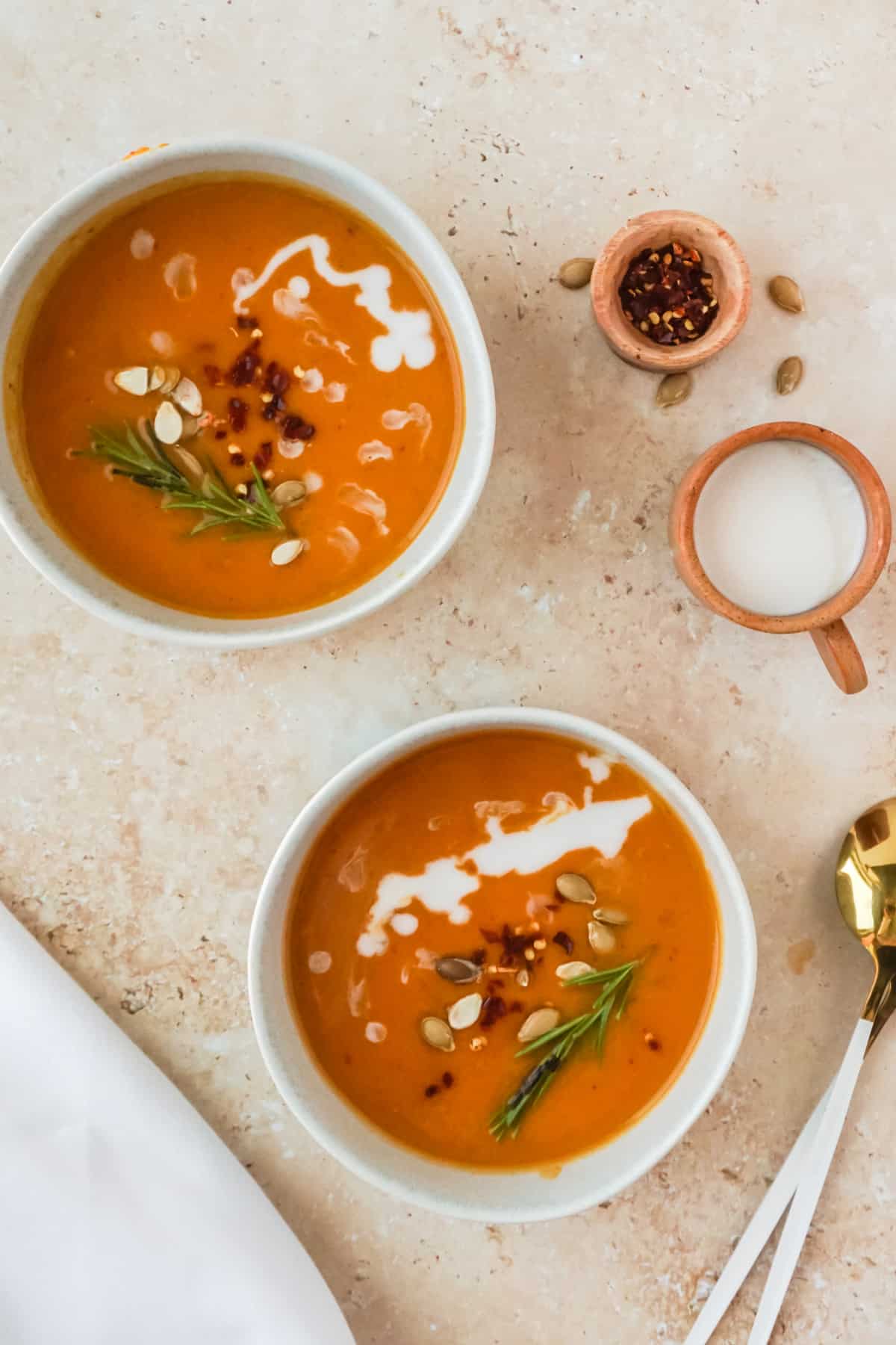 Two bowls of butternut squash soup with a cup of milk.