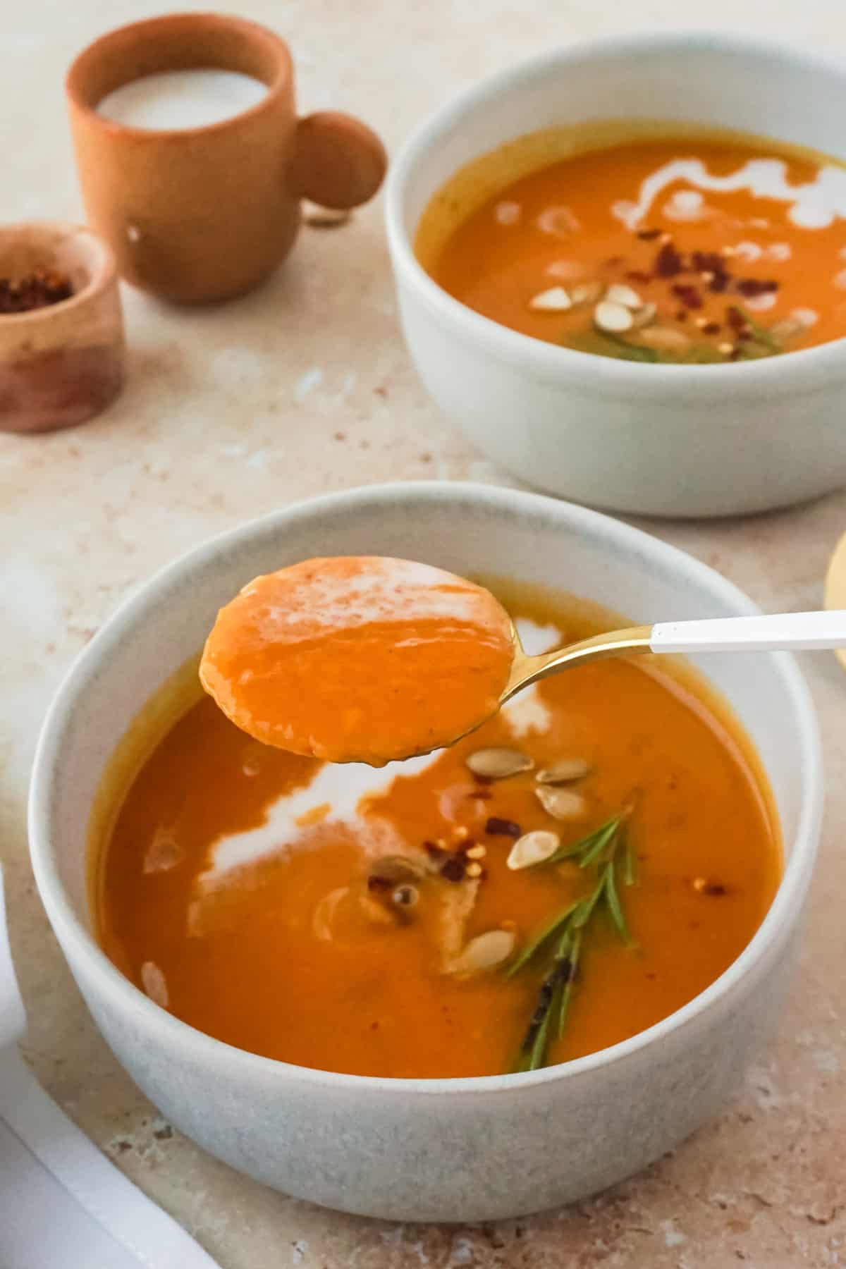 A spoonful full of soup with soups in the background.