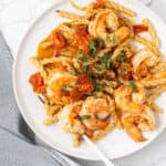 Overhead shot of the shrimp pasta with a green cup of water.
